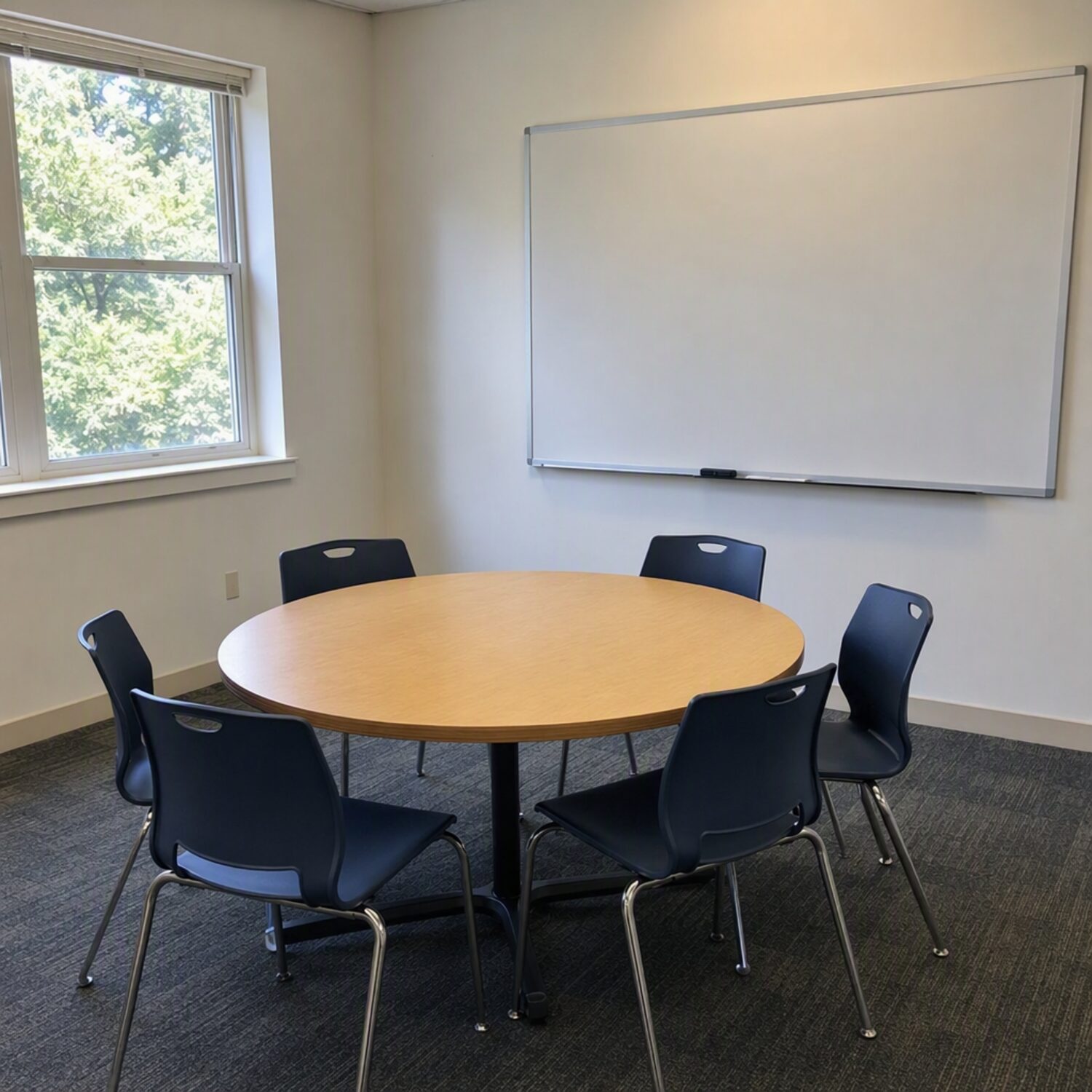 A small classroom with a round table and whiteboard