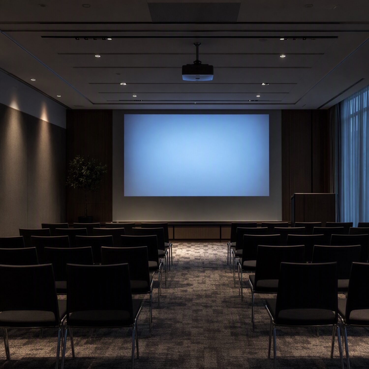 An empty conference room with a lit projector screen