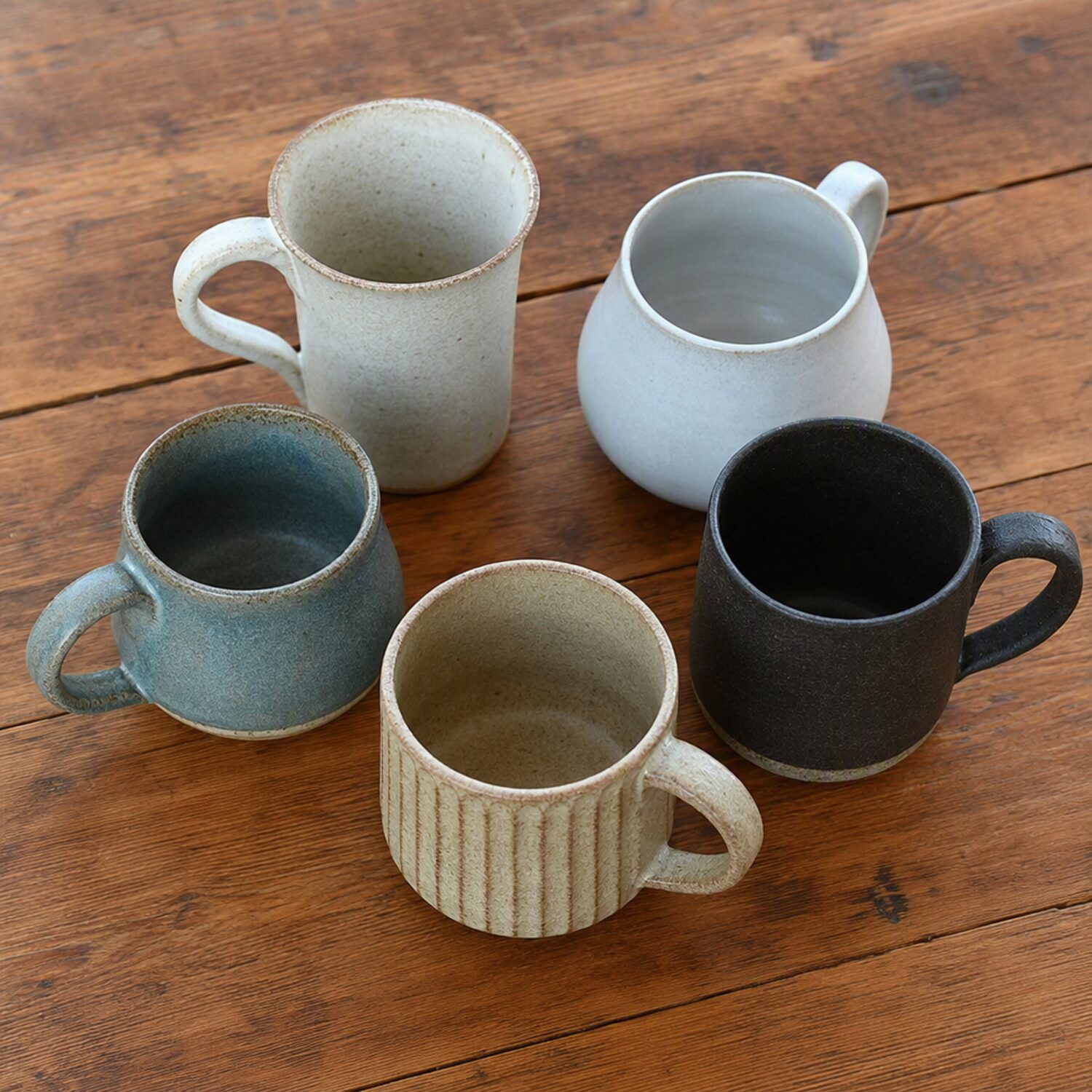Five mugs grouped on a wooden table