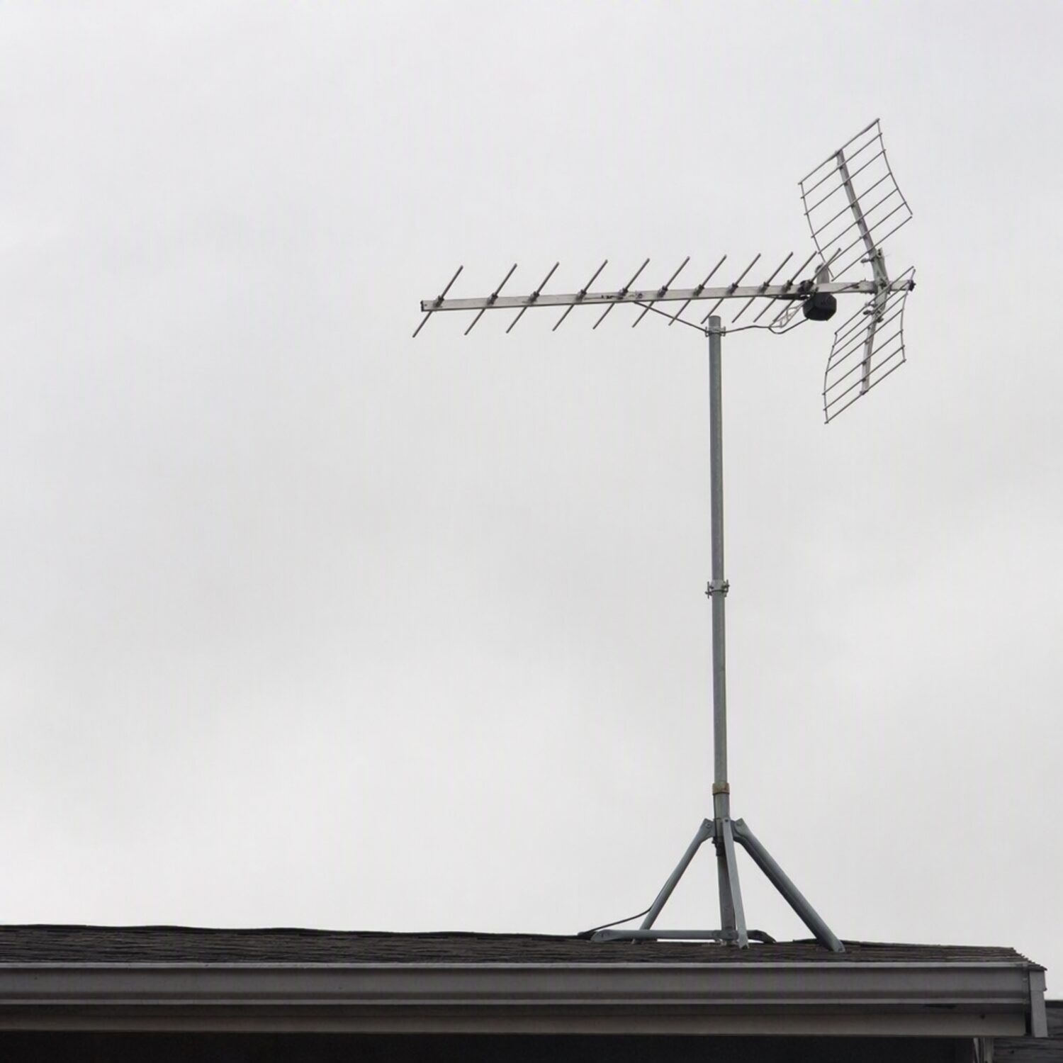 A rooftop antenna against a grey sky
