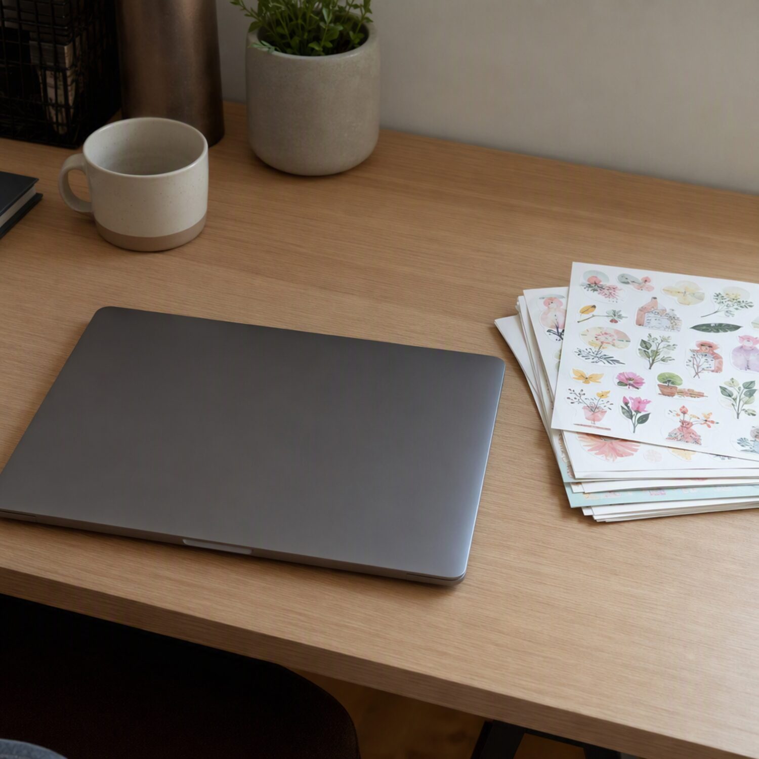 Sticker sheets stacked beside a closed laptop