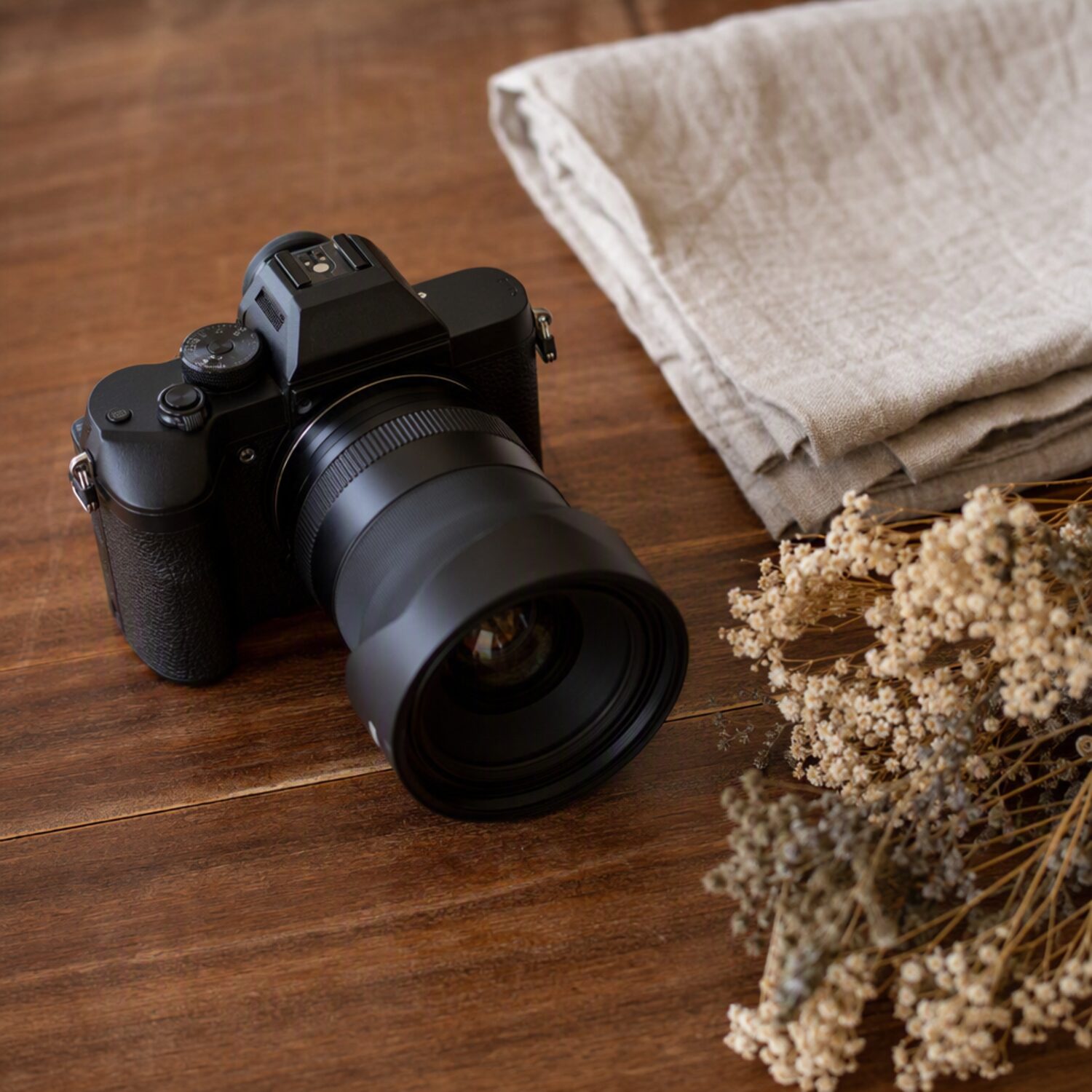 A camera beside dried flowers on a table