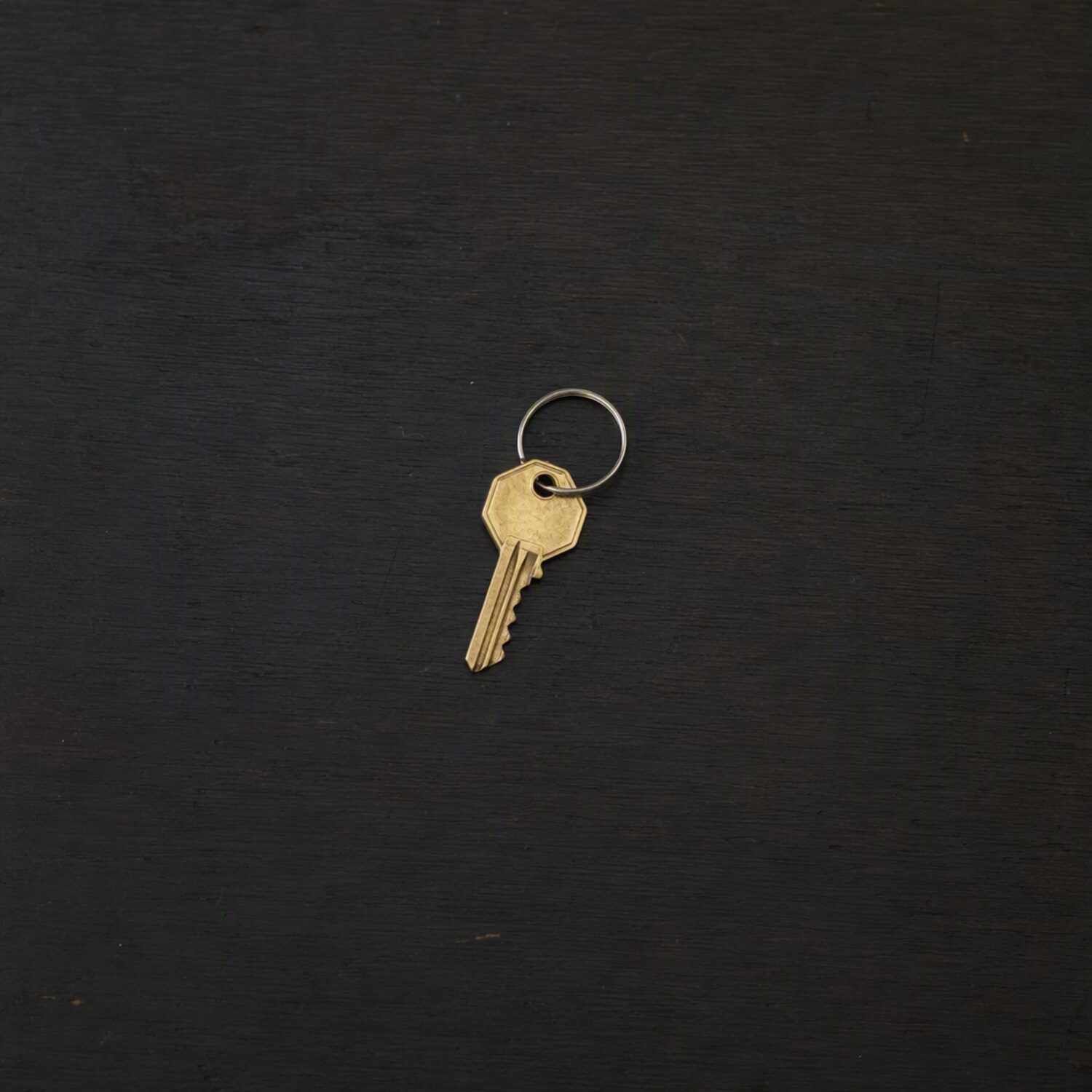 A single brass key on a dark surface