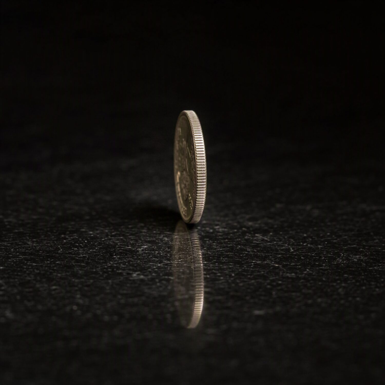 A coin standing on edge on a dark surface