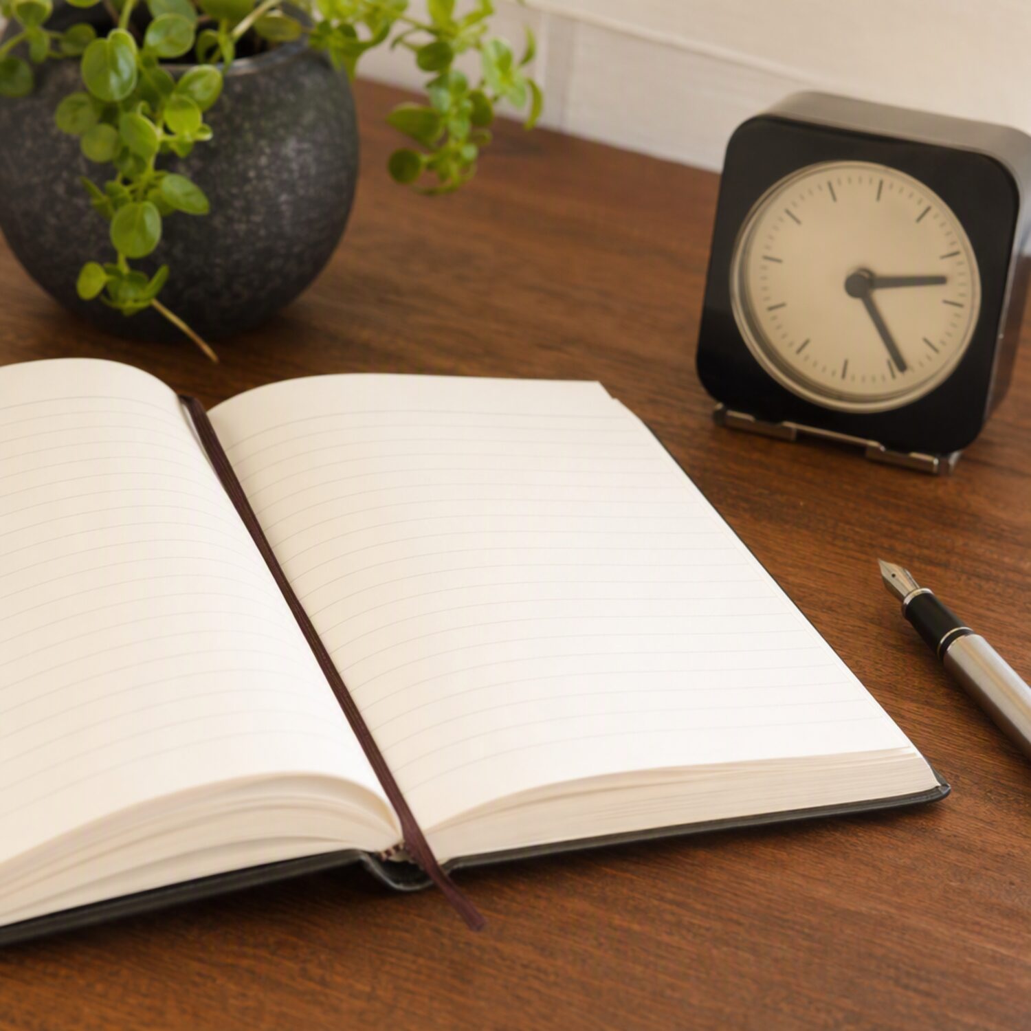 An open diary and clock on a desk