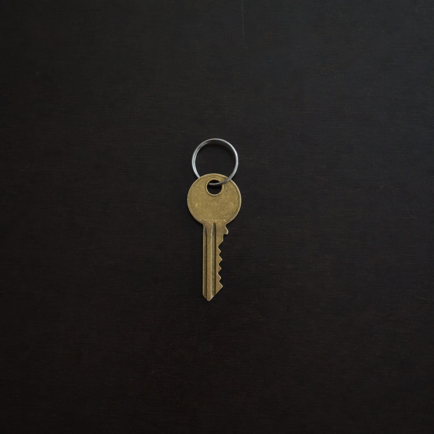 A single brass key on a dark surface