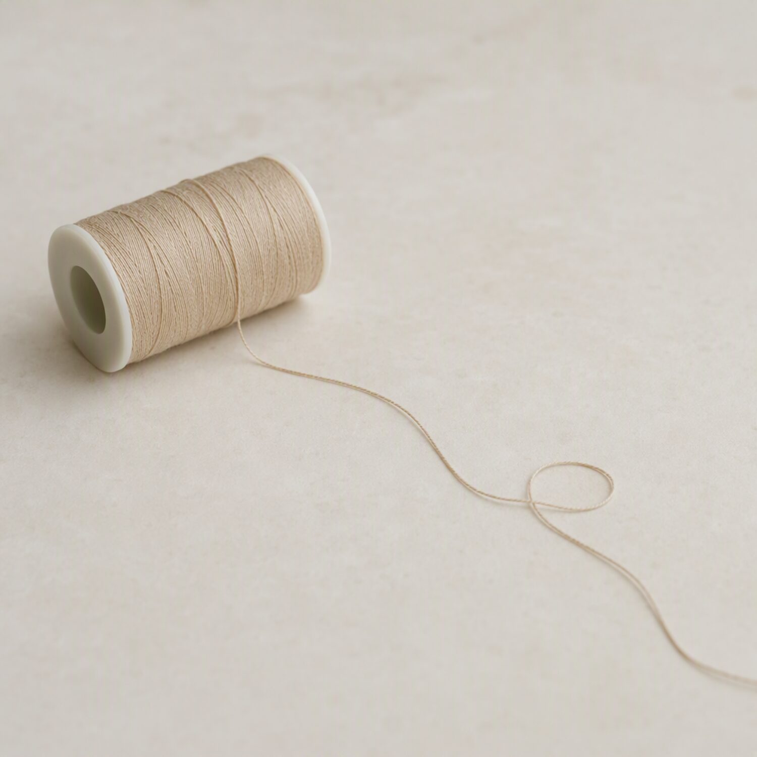 A spool of thread unravelling on a pale surface