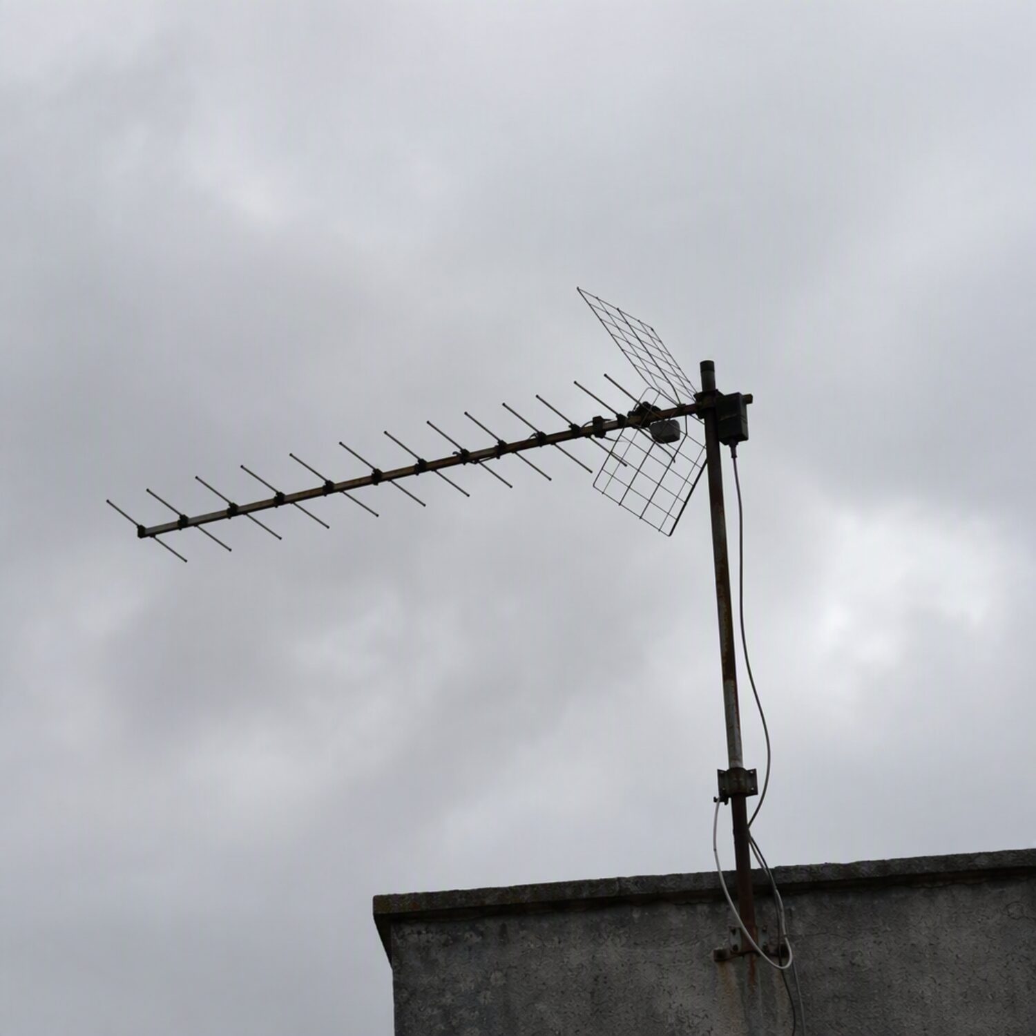 A rooftop antenna against a grey sky