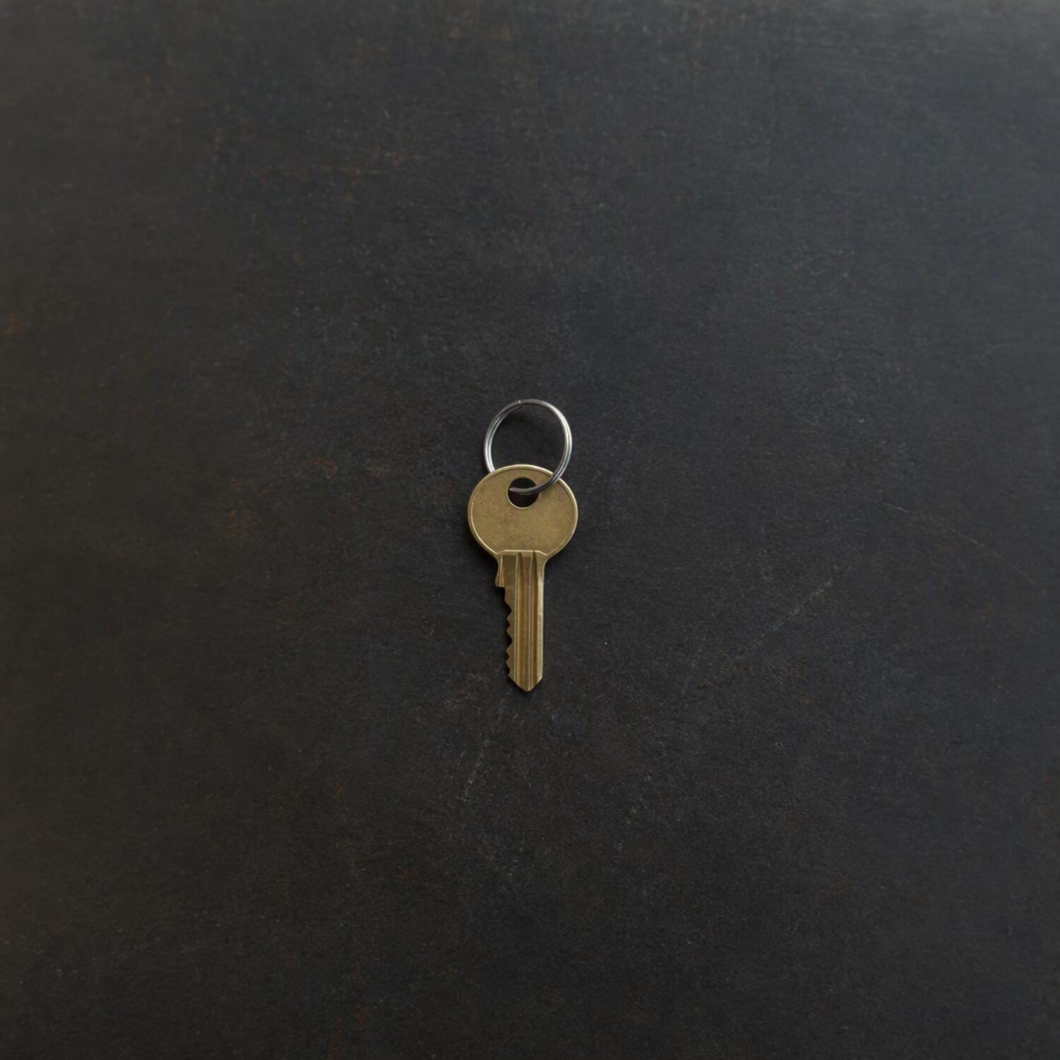 A single brass key on a dark surface