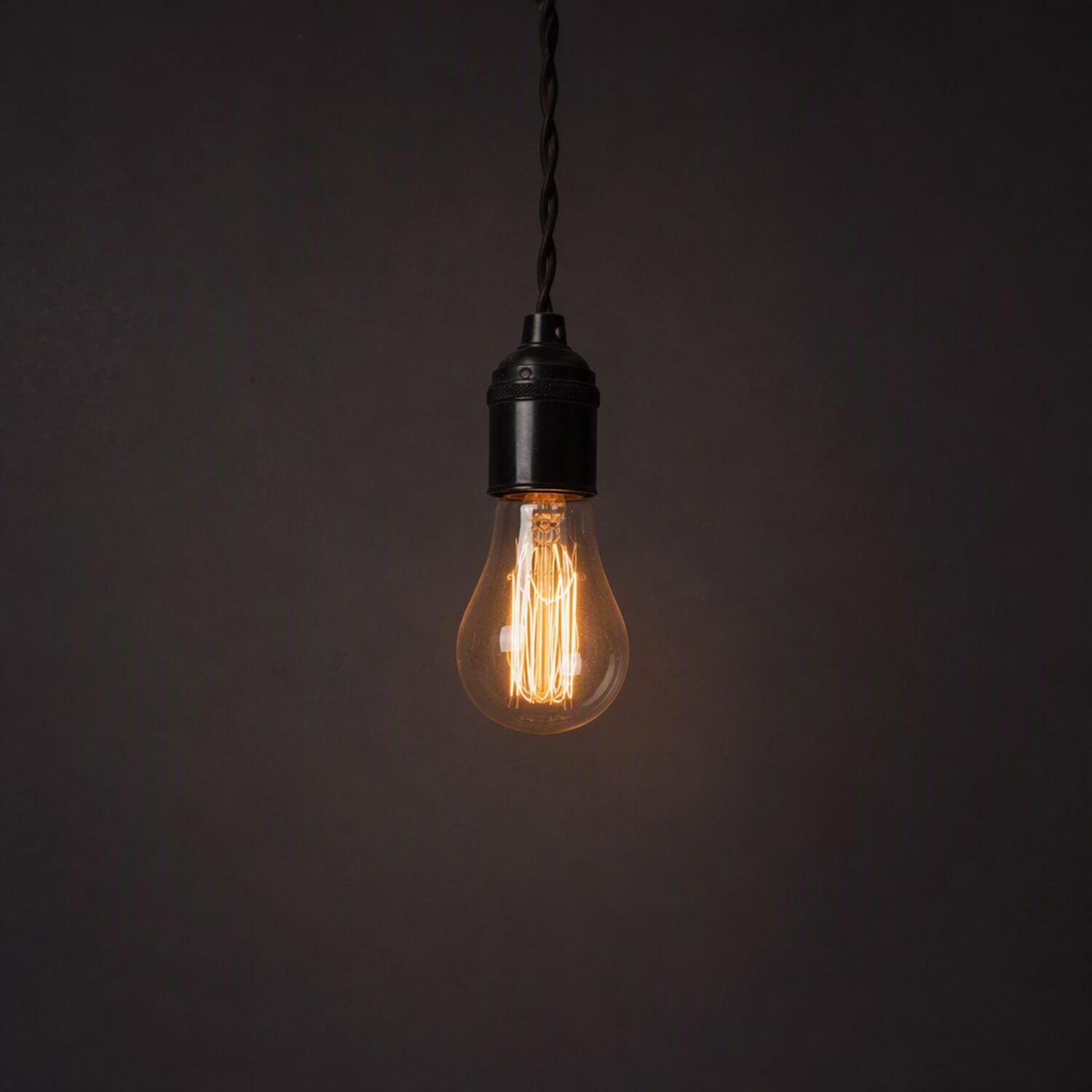 A bare filament bulb against a dark wall