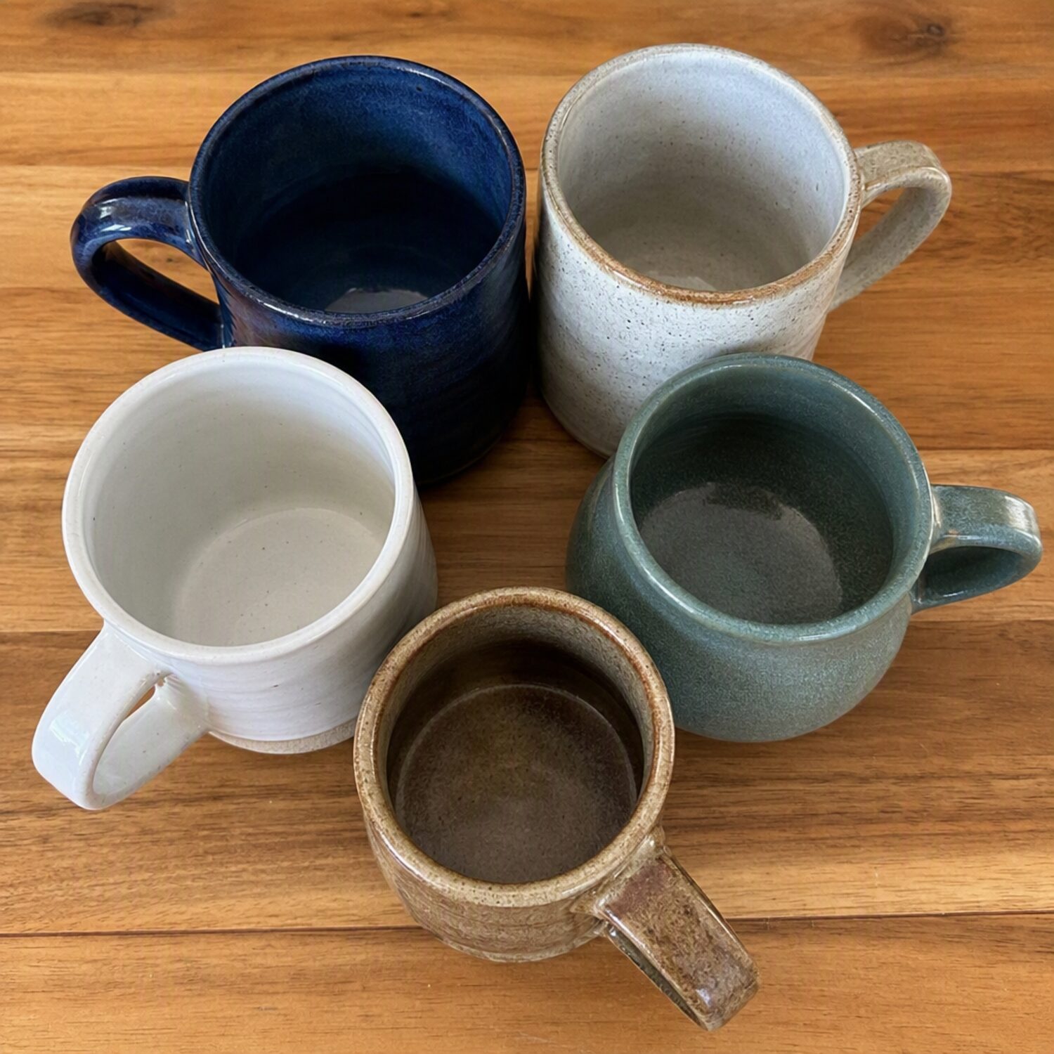 Five mugs grouped on a wooden table