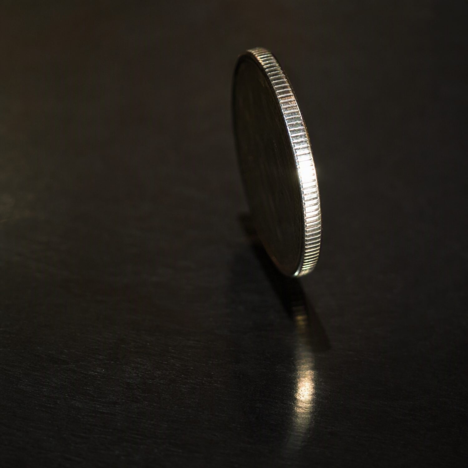 A coin standing on edge on a dark surface