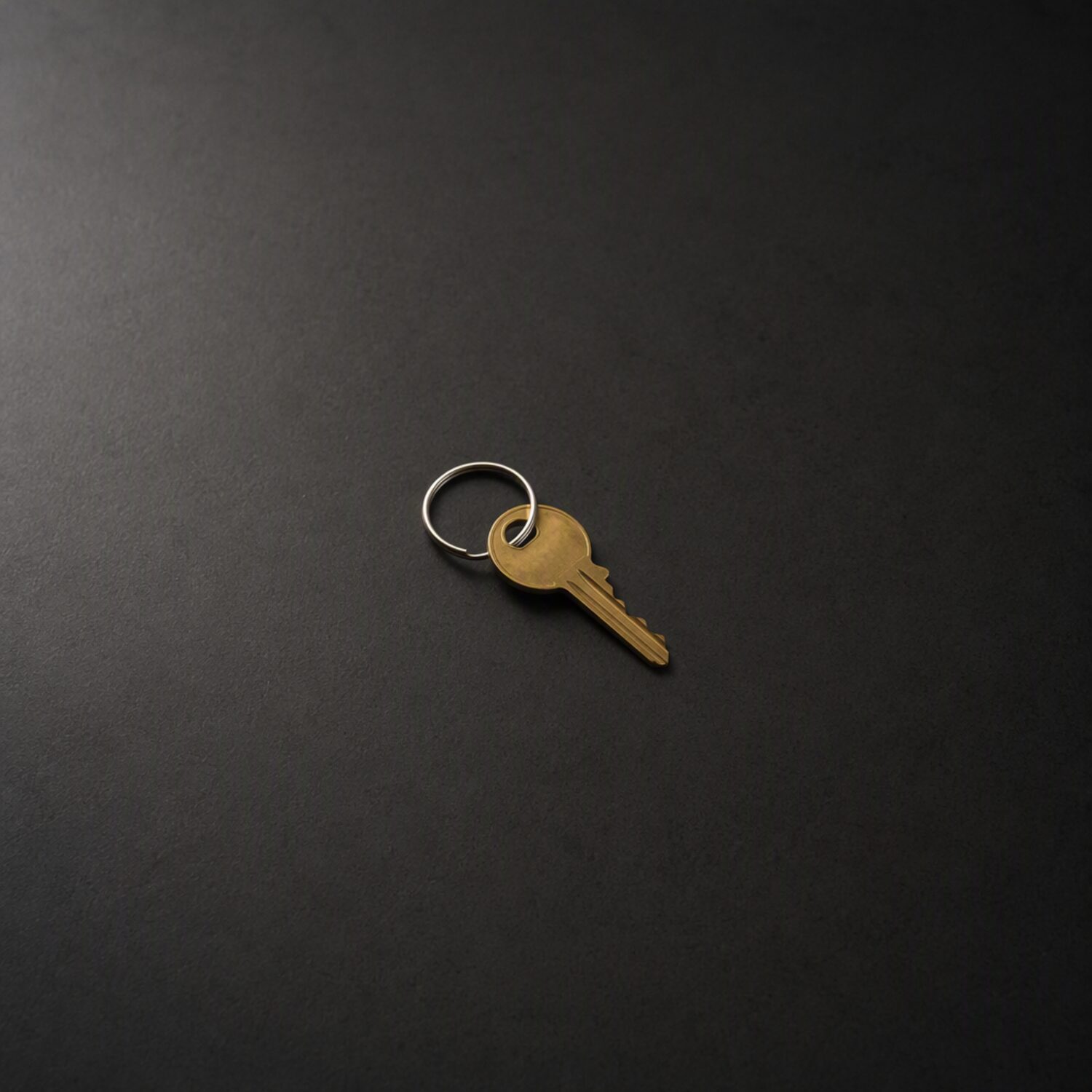 A single brass key on a dark surface