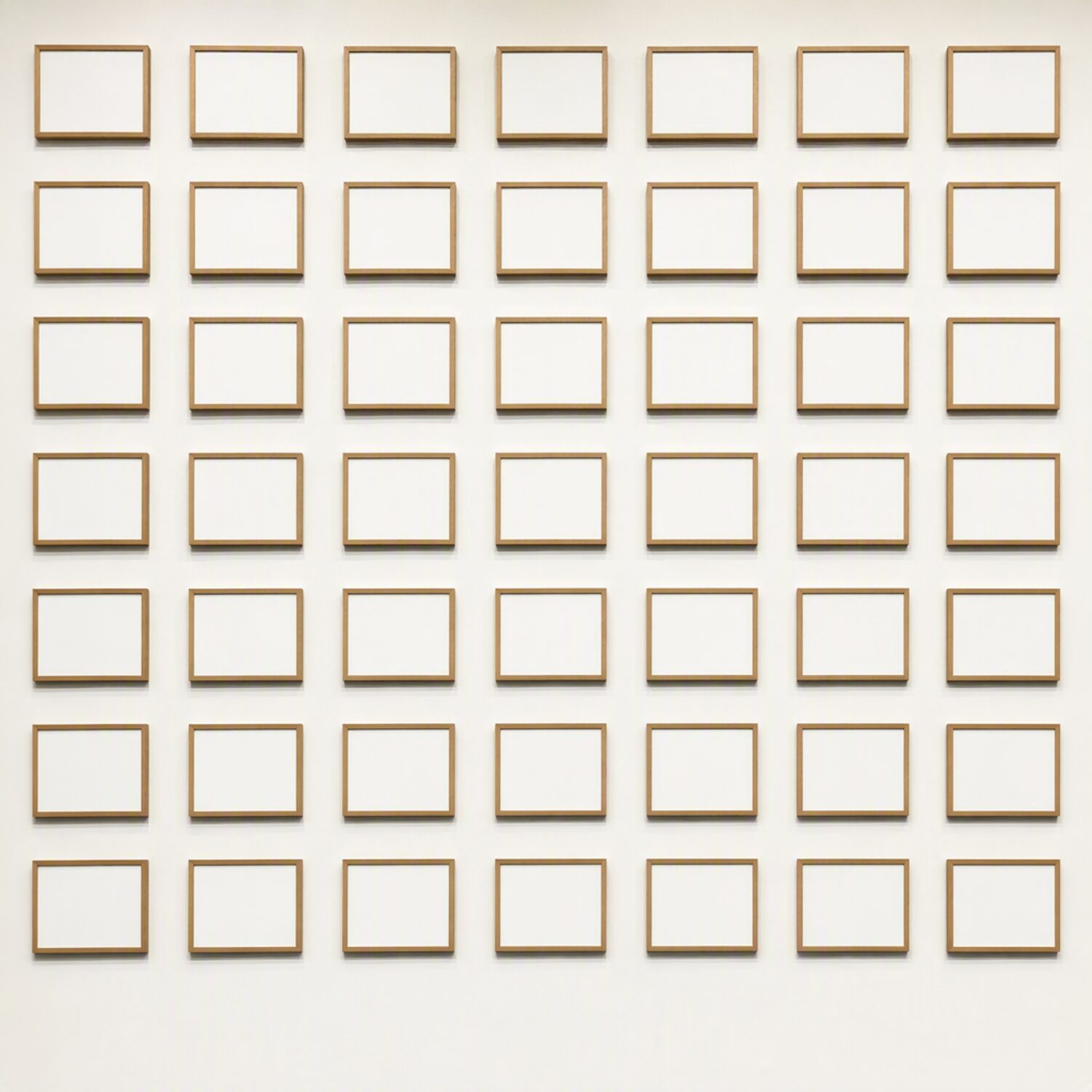 A grid of small blank framed cards on a wall