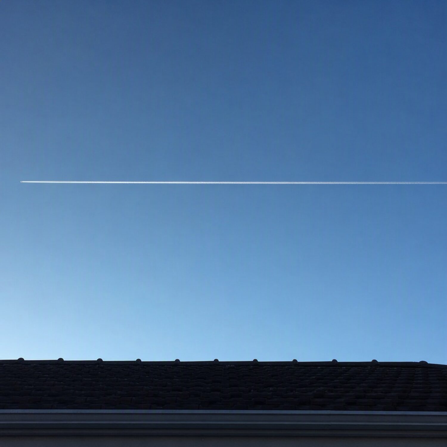A straight contrail across a clear sky